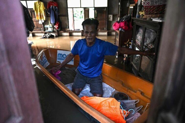 Жители Аюттхаи переправляются на лодках среди затопленных домов.