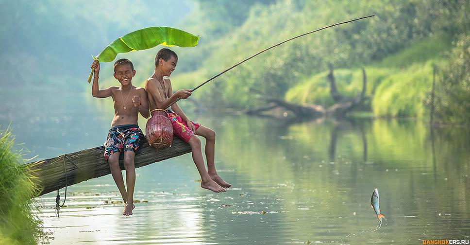 Дети ловят рыбу на реке, прикрываясь листом бамбука